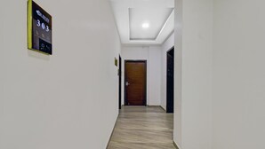 A hallway with a digital display showing the number 303, a wooden door at the end, and a light fixture on the ceiling. - Treebo Premium Brijinn (Nagpur)