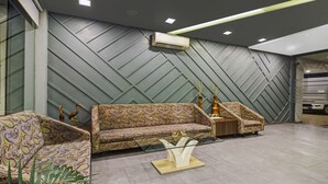 A modern lobby with a herringbone-patterned wall, a patterned sofa, and a glass coffee table. - Treebo Premium Brijinn (Nagpur)