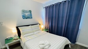 A neatly made bed with striped bedding, a bedside lamp, a nightstand with a bottle and a tissue box, and a painting on the wall. - 2-8 people,3 bedrooms,2 bathrooms, close to Disneyland, safe,quiet,pets friendly (La Puente)