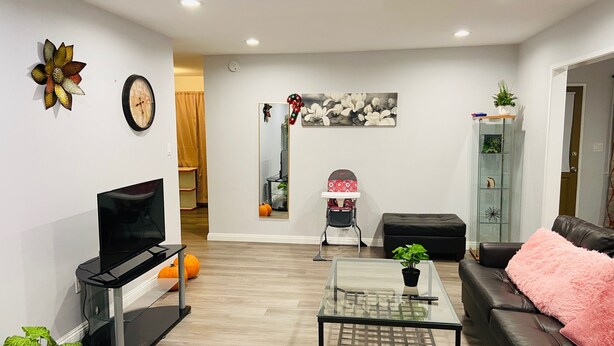 A modern living room with a flat-screen TV, a glass coffee table, a leather sofa, and a pink throw pillow. - 2-8 people,3 bedrooms,2 bathrooms, close to Disneyland, safe,quiet,pets friendly (La Puente)
