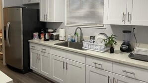 A modern kitchen with white cabinets, stainless steel appliances, a sink, and a window with blinds. - 2-8 people,3 bedrooms,2 bathrooms, close to Disneyland, safe,quiet,pets friendly (La Puente)