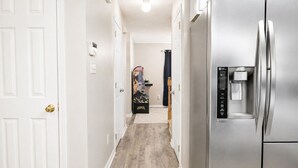 Una cocina con un refrigerador de acero inoxidable, un dispensador de agua y un pasillo que conduce a una habitación con una puerta.