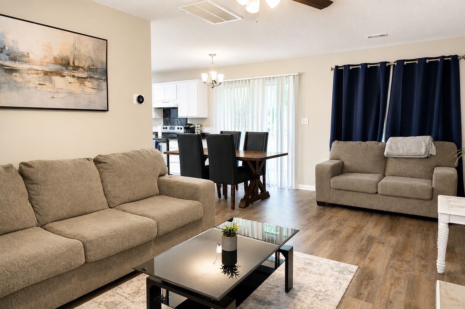 A living room with a sofa, coffee table, and a dining area with chairs and a table.
