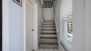 A staircase with a wooden finish, white walls, and a door with a small picture frame.