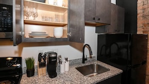 A modern kitchen with dark cabinetry, a built-in coffee maker, and a granite countertop.