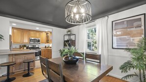 A modern kitchen with wooden cabinets, a central island, and a dining area with a wooden table and chairs. - Zan Court Unit 1 · Mt Lookout Hideaway (Cincinnati)