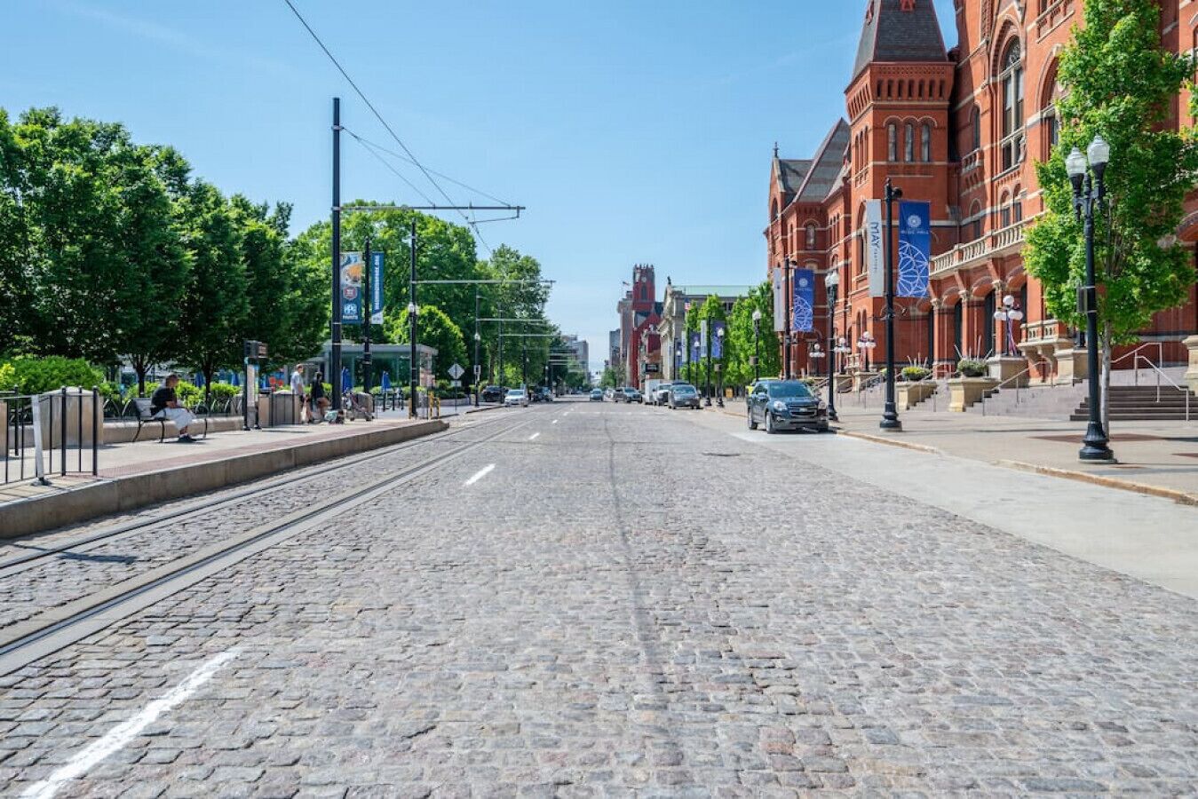 A cobblestone street lined with red brick buildings and a tram track.
