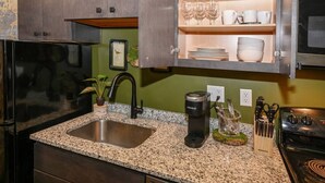 Una cocina con encimeras de granito, cafetera, pileta y bloque para cuchillos.