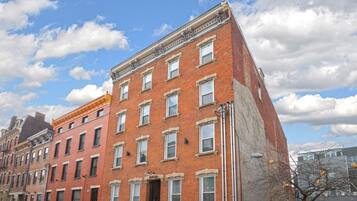 A multi-story brick building with a flat facade, multiple windows, and a corner entrance.