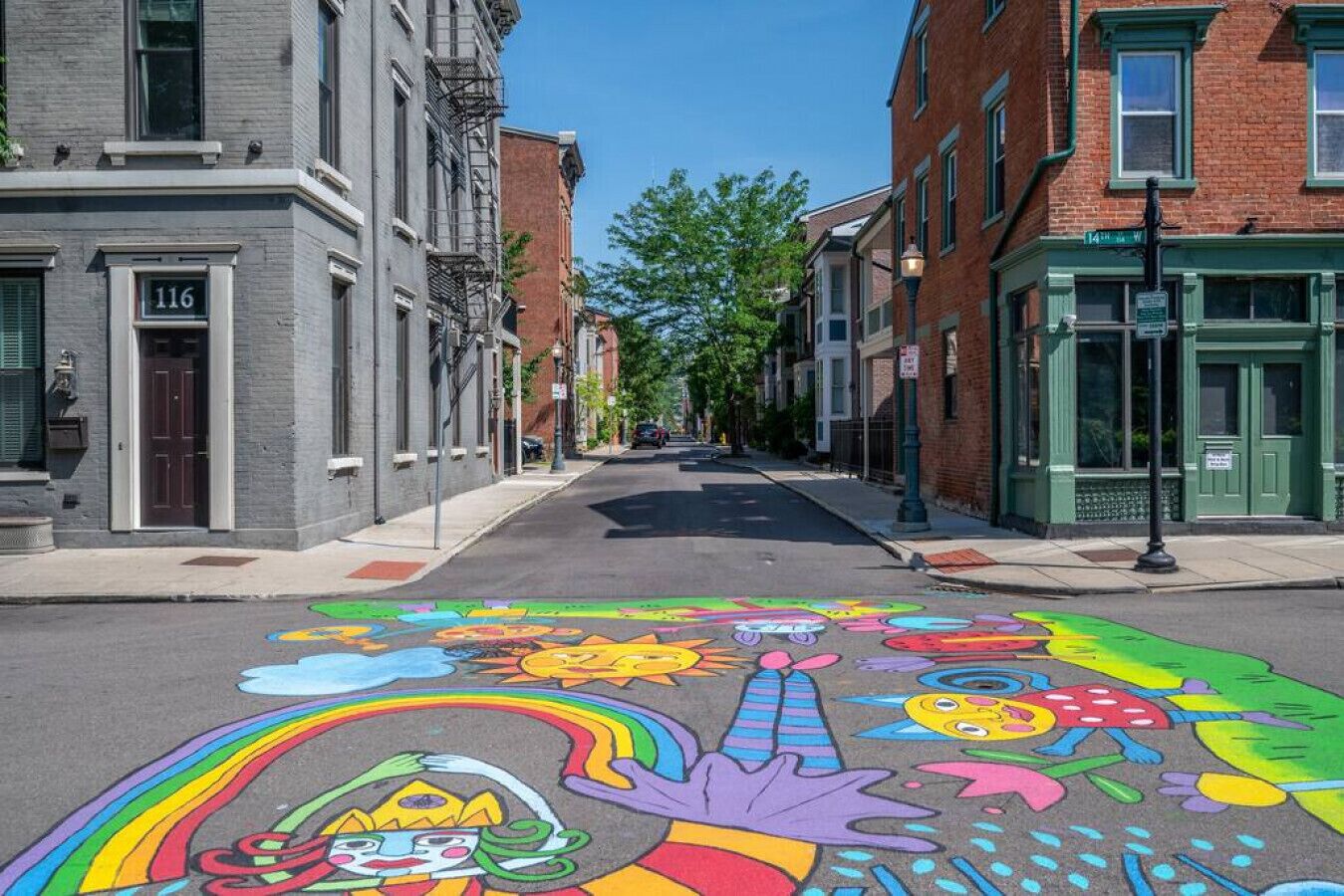 A street with colorful pavement art, buildings, and a clear sky.