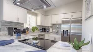 A modern kitchen with white cabinets, a stainless steel refrigerator, a built-in stove, and a potted plant. - Indian Rocks Beach Unit B Star5vacations (Indian Rocks Beach)