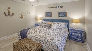 A bedroom with a bed, two nightstands, a ceiling fan, and nautical-themed wall decor. - Indian Rocks Beach Unit B Star5vacations (Indian Rocks Beach)