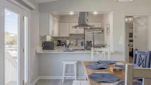 A modern kitchen with white cabinets, a stainless steel refrigerator, and a built-in island with bar stools. - Indian Rocks Beach Unit B Star5vacations (Indian Rocks Beach)