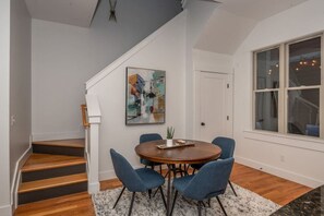Uma sala de jantar com uma mesa redonda, cadeiras azuis e um quadro na parede.