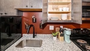 A kitchen with granite countertops, stainless steel appliances, and wooden cabinets. - Rodeo Red | OTR Cincinnati (Cincinnati)