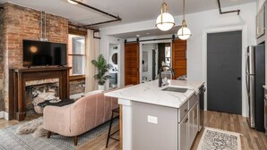 Een moderne keuken met een centraal eiland, een open haard en met bakstenen accentmuren.