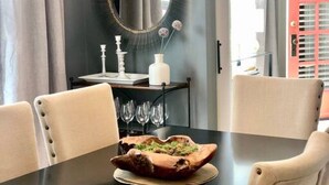 A dining area with a black table, white chairs, a decorative bowl, and a round mirror on the wall. - Lower Cambridge · Cozy Cambridge (Cincinnati)