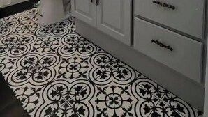 Un baño con lavamanos blanco, espejo y baldosas de suelo estampadas.