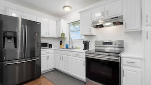A modern kitchen with white cabinetry, stainless steel appliances, and a built-in oven. - Central Houston - Bright and Spacious Modern Mid - 4 miles to DT (Houston)
