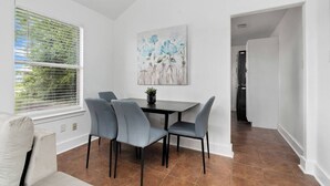 A dining area with a table and chairs, a painting on the wall, and a view through the window. - Central Houston - Bright and Spacious Modern Mid - 4 miles to DT (Houston)