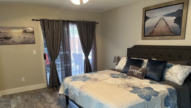 A bedroom with a bed, curtains, a painting, and a view of the outdoors. - New family retreat w/private heated pool and hot tub (Chandler)