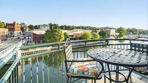 Un balcon avec une table et une chaise, donnant sur un canal, avec des bâtiments en arrière-plan.