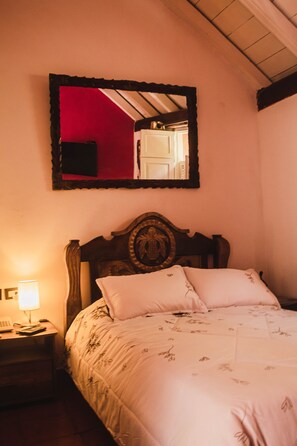 A bedroom with a wooden headboard, a bed with floral bedding, a nightstand with a lamp, and a mirror on the wall. - SD-4 HABITACION EN LA CIUDAD ANTIGUA (Cartagena)