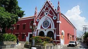 Un edificio rojo con un estilo arquitectónico distintivo, que incluye un tejado puntiagudo y detalles decorativos.
