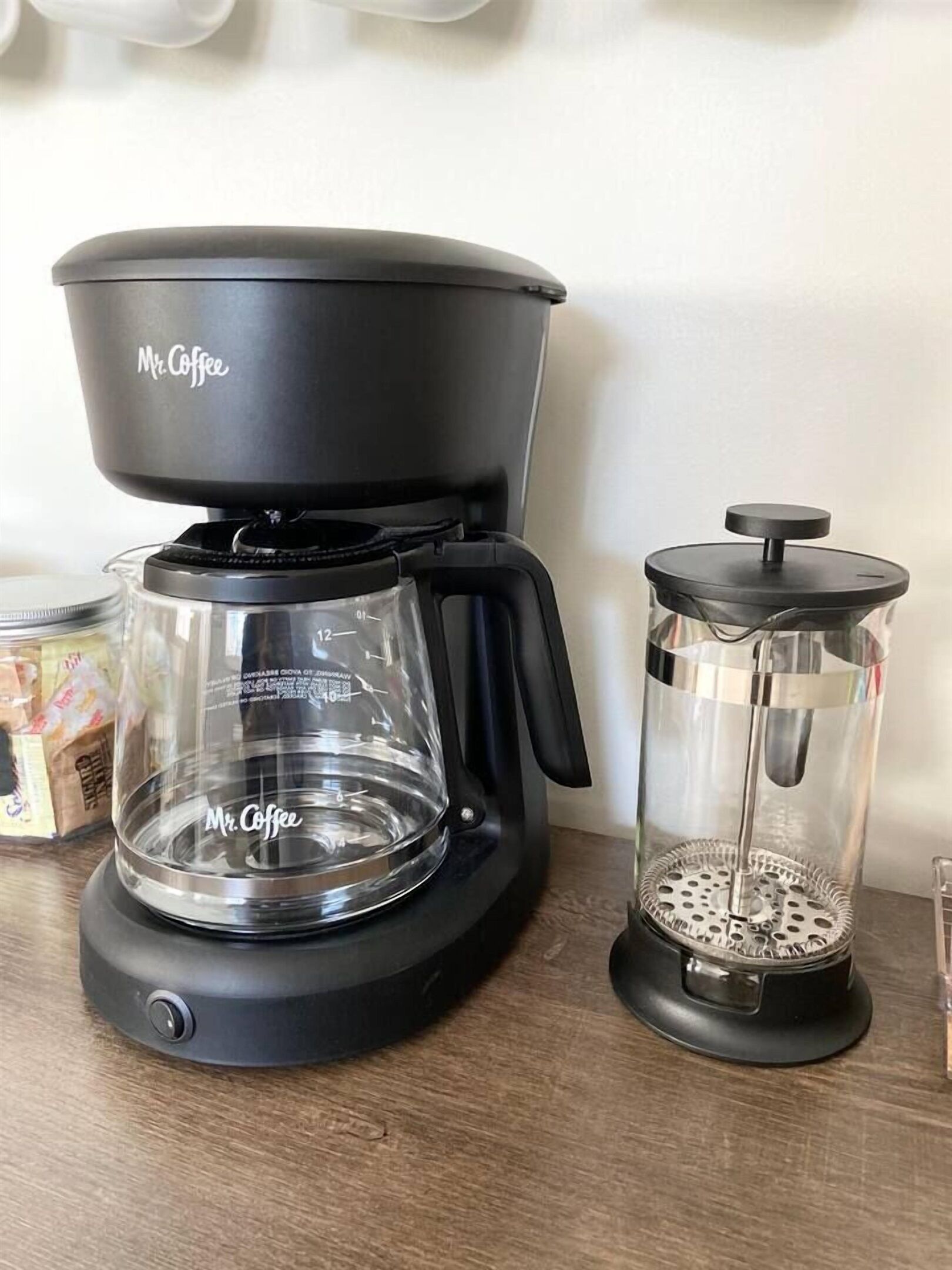 A Mr. Coffee coffee maker and a French press on a wooden surface.