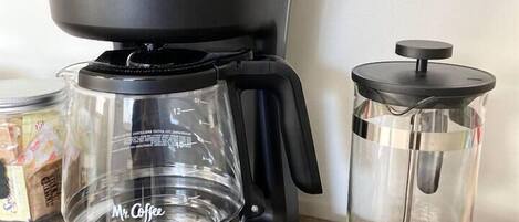 A Mr. Coffee coffee maker and a French press on a wooden surface.
