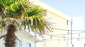 Una casa a due piani con un portico bianco e una palma.