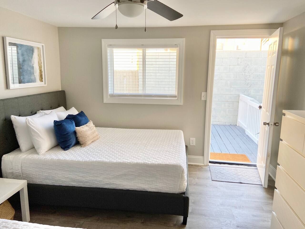 Een slaapkamer met een bed, een plafondventilator, een raam en een deur die leidt naar een balkon.