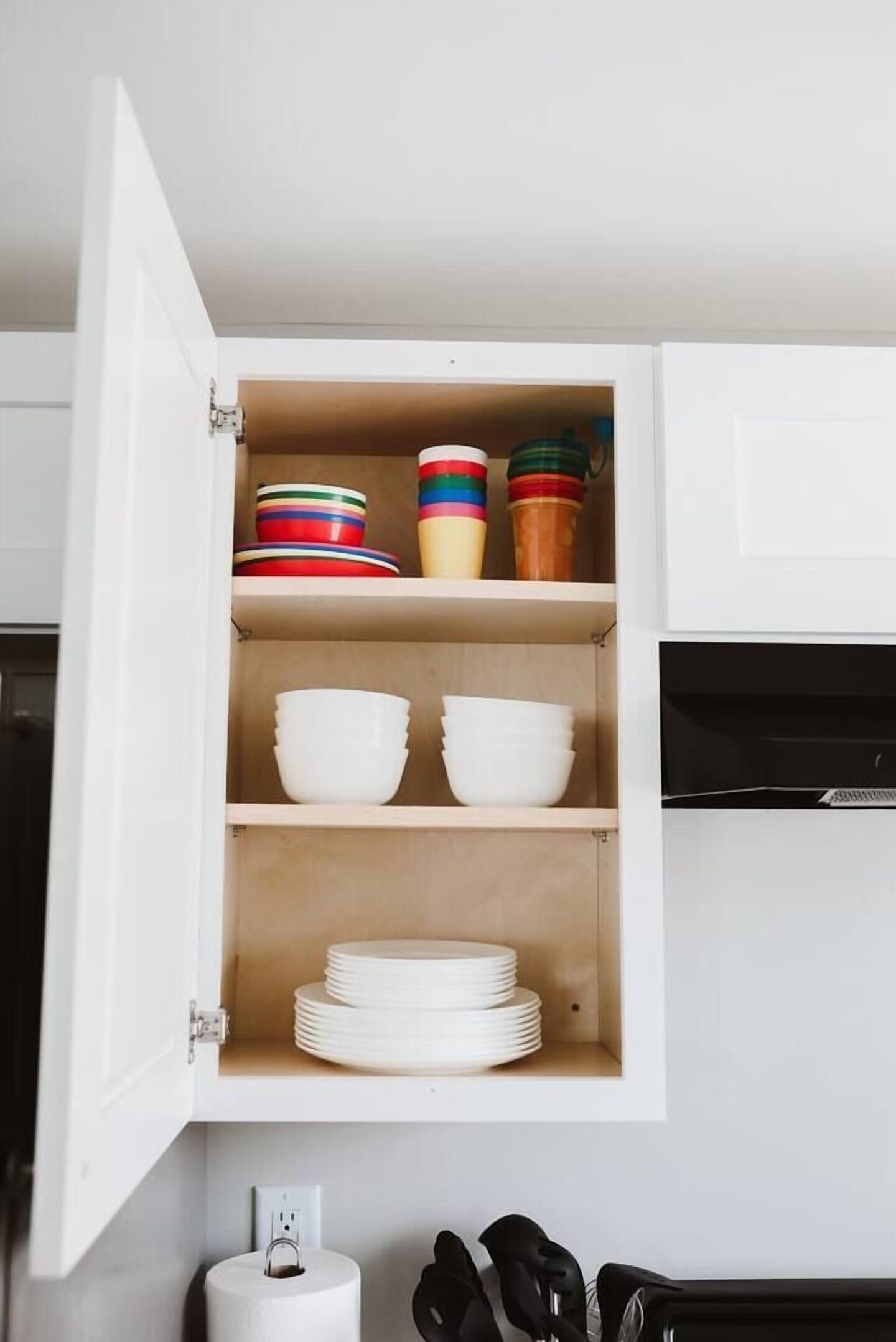 Un meuble de cuisine avec des placards blancs, un plan de travail blanc et un appareil électroménager noir.
