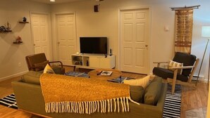 Una sala de estar con un sofá, sillones, una mesa de centro, un televisor y un ventilador de techo.
