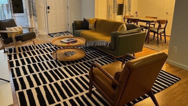Una sala de estar con sofá, sillones, una mesa de centro y una alfombra estampada.