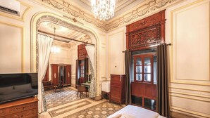 Una habitación de hotel con una cama grande, televisión, escritorio y armario.