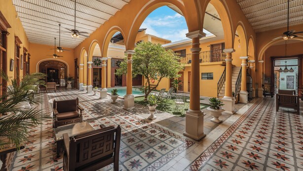 Un patio amplio con piscina, suelo de baldosas y varias zonas de estar.
