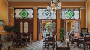 Un vestíbulo amplio con suelo estampado, mobiliario de madera y ventanas grandes con diseños de vidrio verde.