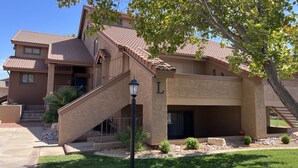 A two-story house with a tiled roof, a front staircase, and a well-maintained lawn.