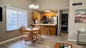 A modern kitchen with wooden cabinets, stainless steel appliances, and a dining area with a wooden table and chairs.