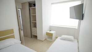 A bedroom with two beds, a wardrobe, a bedside table, a TV, and a window. - 2TC10-J APARTAMENTO FRENTE AL MAR (Cartagena)