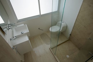Ein modernes Badezimmer mit Duschkabine aus Glas, einem weißen Waschbecken und einer Toilette.