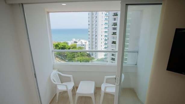 A balcony with a glass door, white plastic chairs, and a small table. - 2TC10-J APARTAMENTO FRENTE AL MAR (Cartagena)