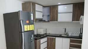 A modern kitchen with a stainless steel refrigerator, a microwave, and a stove. - 2TC10-J APARTAMENTO FRENTE AL MAR (Cartagena)