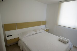 Ein Schlafzimmer mit Bett, Nachttisch, Fernbedienung und Fenster.