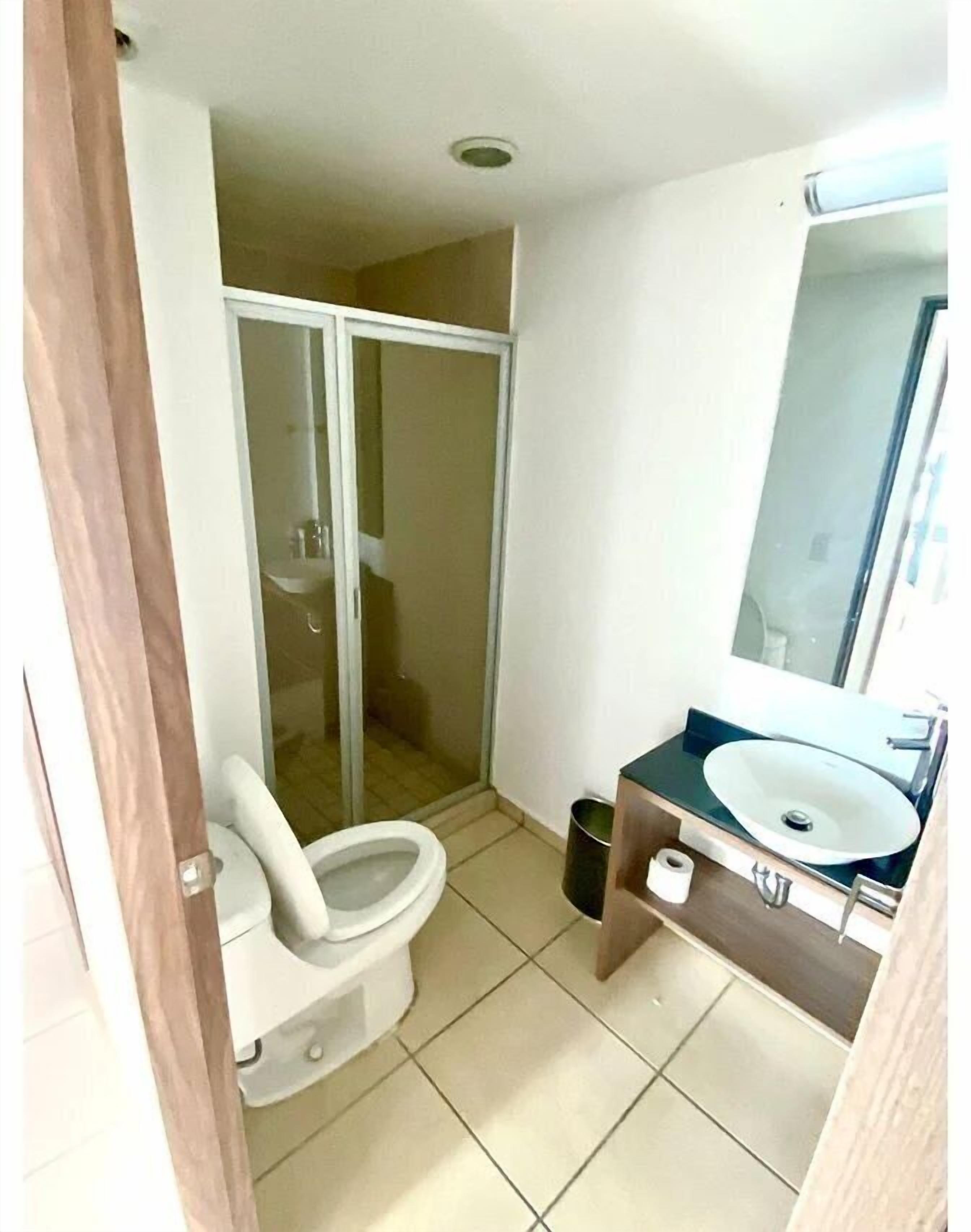 A small bathroom with a toilet, a sink, and a shower.