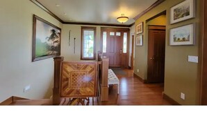 A hallway with wooden flooring, a bench, and framed artwork on the walls. - Executive House Suite with Gorgeous Olympic Views (Port Angeles)
