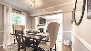 A dining area with a dark wooden table, four chairs, and a patterned rug. - Beautiful 3 Bedroom Townhouse (Greensboro)