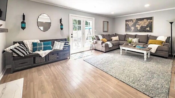 A spacious living room with a grey sofa, a white coffee table, and a grey rug. - Beautiful 3 Bedroom Townhouse (Greensboro)