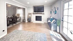 A spacious living room with a fireplace, a dining area, and a large window. - Beautiful 3 Bedroom Townhouse (Greensboro)